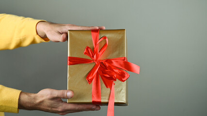 A man holding a gift box with a red bow