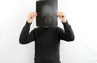 Man on white background holding a skull x-ray in his hand in front of his face. Skull