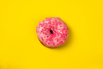 Pink donut with pink sprinkles isolated on yellow background.Pink tasty dough