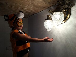 little child in a tiger costume held out his hands to the light of the lanterns. Little girl in the twillight