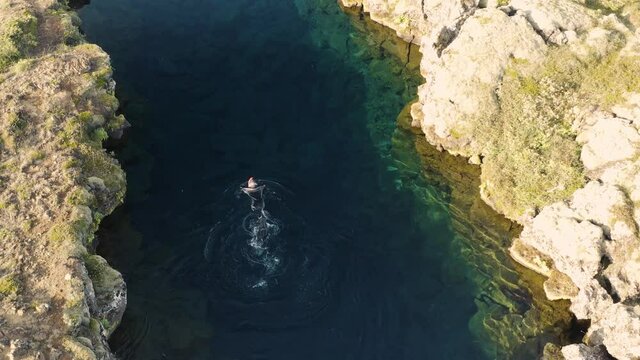 Aerial: Snorkeler swimming in Silfra popular diving / snorkeling fissure in Iceland between Eurasian and North American tectonic plates Thingvellir national park Phenomenal water clarity