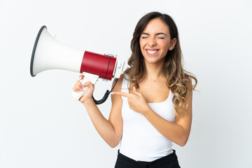 Young caucasian woman isolated on white background holding a megaphone and pointing side