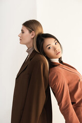 young stylish model posing with brunette asian woman on white