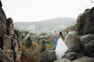 Beautiful gorgeous bride posing to groom and having fun near at mountains with amazing view, space for text, wedding couple