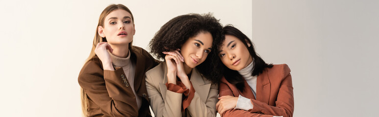 pretty interracial women in pastel formal wear posing on white, banner