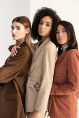 interracial young women in pastel formal wear posing on white