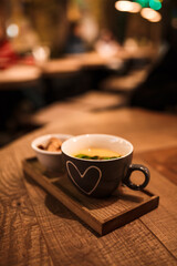 Serving cream soup in a cup with a cup of rusks on a wooden tray