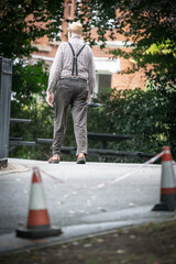 An Old Man Carrying An Umbrella Walking Out Of A Park