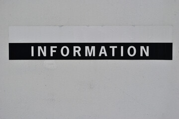 Prominent 'Information' Sign Painted on White Wall  