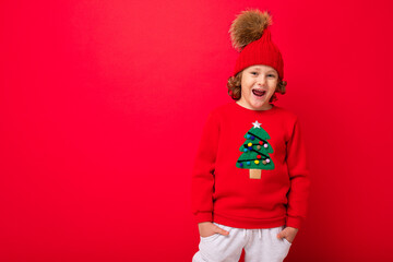 boy model on a red background, portrait of a cool blonde with curls in a sweater with a Christmas tree
