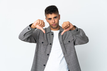 Young brazilian man isolated on white background showing thumb down with two hands