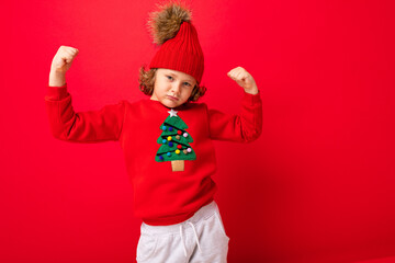 cool boy with curls on a red background in a sweater with a christmas tree