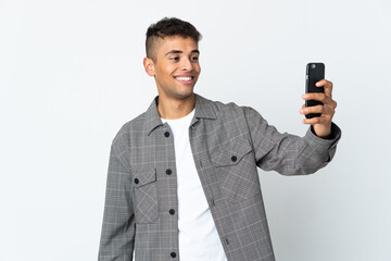 Naklejka premium Young brazilian man isolated on white background making a selfie