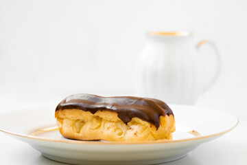 Eclair  with chocolate topping on serving plate.  Appetizing dessert and pastries.