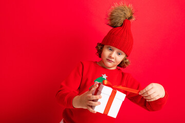curly blond boy with a gift in his hands on a red background