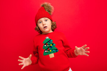 cool boy with curls on a red background in a sweater with a christmas tree