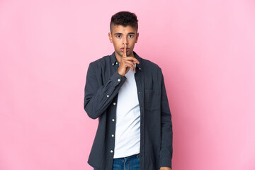 Young Brazilian man isolated on pink background showing a sign of silence gesture putting finger in mouth