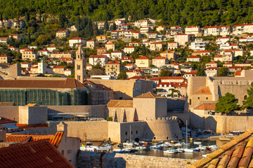 Bay area in the port of Dubrovnik, waterside of the city walls. Boats anchored and a church...