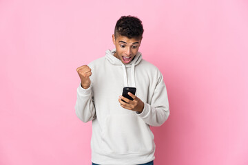Young Brazilian man isolated on pink background surprised and sending a message