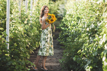 Fototapeta na wymiar Attractive young lady with sunflower. Beautiful woman outdoors at summer.