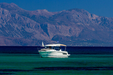 Fototapeta na wymiar Moden boat on a clear ocean with mountainous backdrop