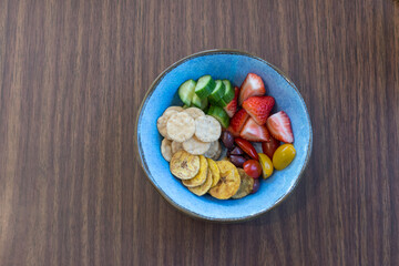 Healthy snack for young child: crackers, cucumbers, strawberries, tomatoes, olives, and banana chips