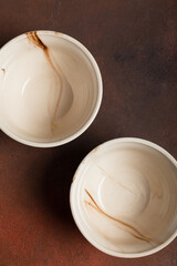 Two light handmade cups on a brown background