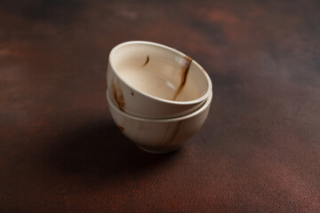 Two light handmade cups on a brown background