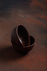 Obraz na płótnie Canvas Two dark handmade clay bowls on brown background