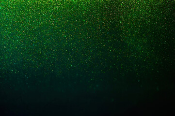 Christmas light background. Sparkling magical dust particles. Falling glitters on green background. 