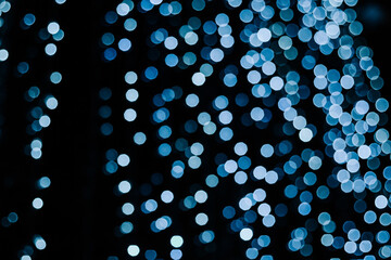 Blue and white bokeh on a dark background. Festive illumination. Christmas lights.