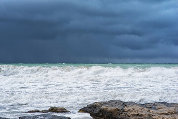 Autumn sea landscape. Rough sea with waves during autumn stormy weather. Dark heavy clouds in the sky. Dark and dramatic storm clouds background.