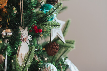 White wooden toy cat hangs on the Christmas tree copy space. Wooden Christmas toys.