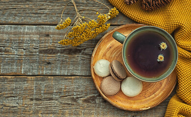 Autumn, fall leaves, hot steaming cup of tea and a warm scarf on rustic wooden table background. Seasonal, morning tea, sunday relaxing on the garden and still life.