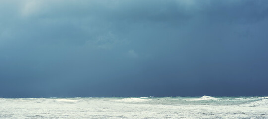 Autumn sea landscape. Rough sea with waves during autumn stormy weather. Dark heavy clouds in the sky. Dark and dramatic storm clouds background.