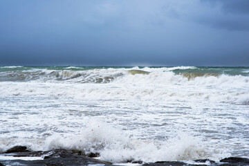 Autumn sea landscape. Rough sea with waves during autumn stormy weather. Dark heavy clouds in the sky. Dark and dramatic storm clouds background.
