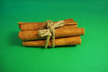 several brown cinnamon sticks tied with thread on a green background top view . Christmas symbols...