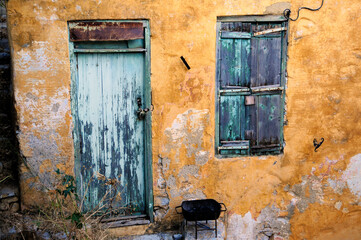 A building as old as time itself, Symi island, Greece. Grey-green wooden window and door, ochre walls.