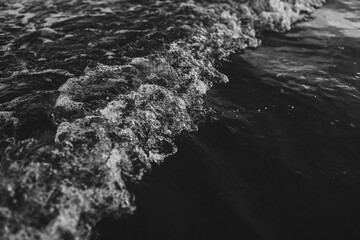 Grayscale shot of a foamy wave in Dunedin, New Zealand