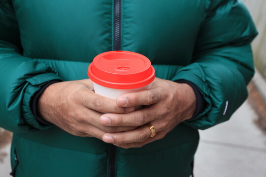 Young man holding coffee cup outside