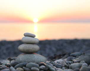 Pyramid of stones against the background of the sea and colorful sunset. Selective focus