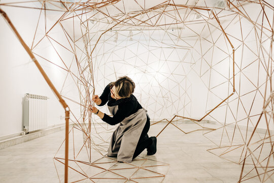 Female Artist Working On A Large Metal Sculpture In The Empty Art Gallery