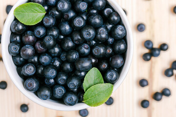 Fresh bilberries in a cup on the wooden table. Macro shot. Top view.