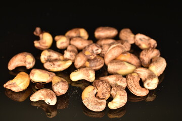 Fragrant fried salted cashews, close-up, isolated on black.