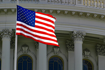 American flag in front of Capitol Hill in Washington DC with dome in daylight and facade details