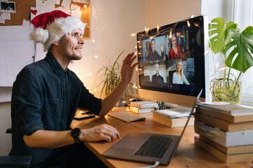 Young man having Zoom video call via a computer in the home office. Christmas Day party. Virtual...