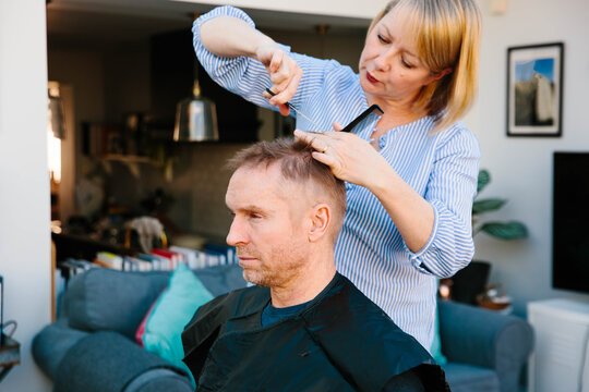 Woman cutting her husband's hair at home