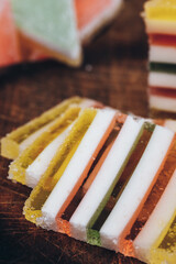 Sliced multicolored striped marmalade on wooden table. Colorful jelly candy close-up. Macro shot, selective focus.