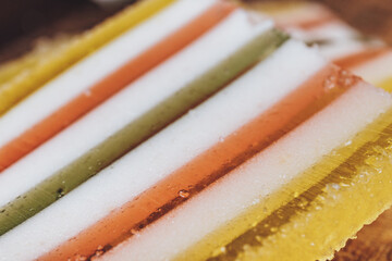 Slice of multicolored striped marmalade close-up. Colorful jelly candy close-up. Macro shot, selective focus.