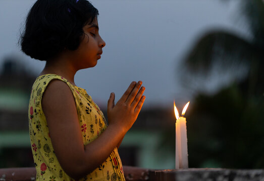 Girl offering prayer at sunset with candles